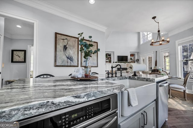 kitchen featuring dark wood-type flooring, ornamental molding, light stone countertops, and a chandelier