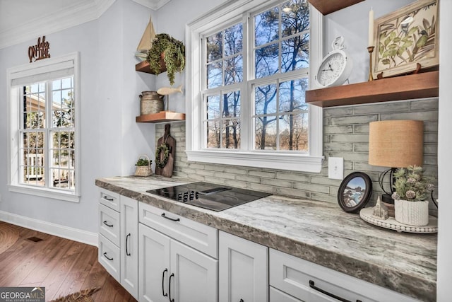 kitchen with light stone counters, white cabinetry, tasteful backsplash, plenty of natural light, and black electric stovetop