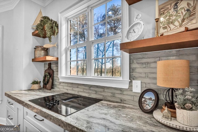 kitchen featuring crown molding, tasteful backsplash, black electric cooktop, light stone countertops, and white cabinets