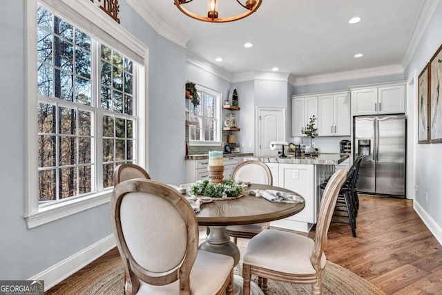 dining room with crown molding, a chandelier, and light hardwood / wood-style flooring