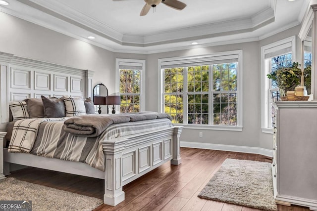 bedroom featuring crown molding, dark hardwood / wood-style floors, ceiling fan, and a tray ceiling