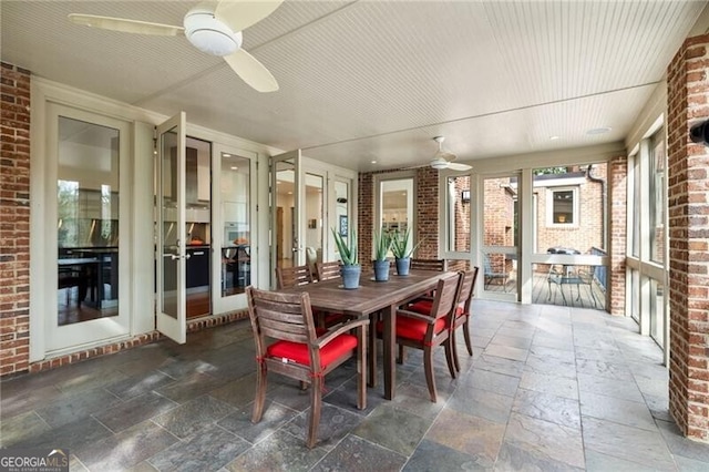 dining space featuring ceiling fan and brick wall