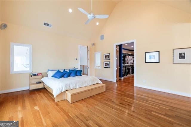 bedroom with a walk in closet, hardwood / wood-style floors, and multiple windows