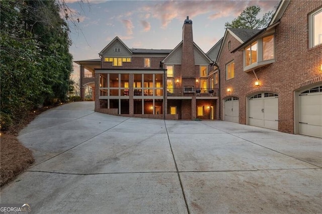 back house at dusk with a balcony and a garage