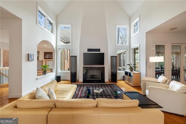 living room featuring high vaulted ceiling, a fireplace, and light hardwood / wood-style floors