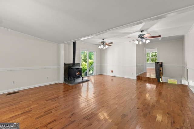 unfurnished living room with a wealth of natural light, wood-type flooring, and a wood stove