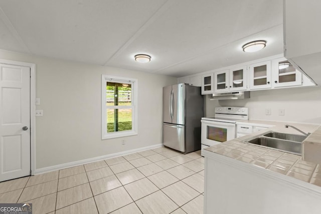 kitchen with sink, stainless steel refrigerator, white range with electric stovetop, white cabinets, and tile countertops