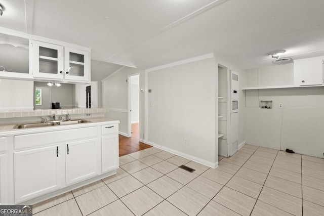 kitchen featuring light tile patterned floors, sink, and white cabinets