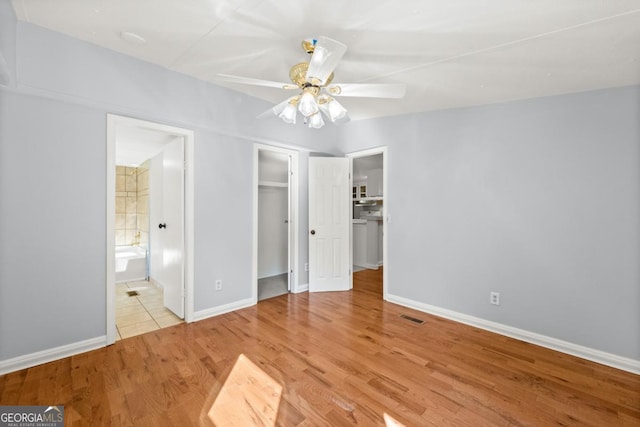 unfurnished bedroom featuring ensuite bath, light hardwood / wood-style floors, a closet, and ceiling fan