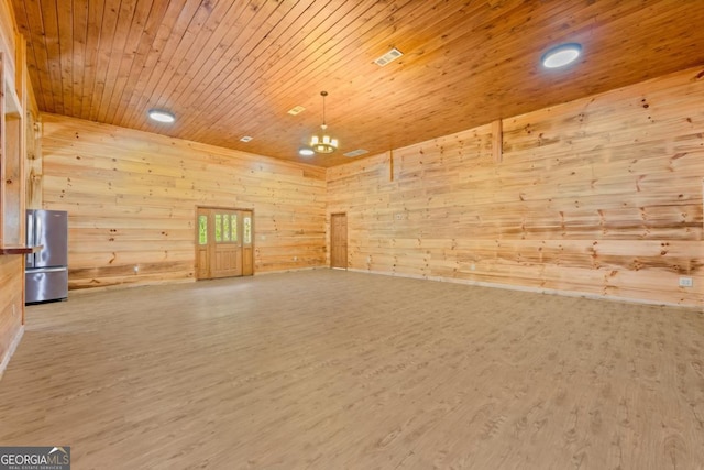 empty room featuring an inviting chandelier, hardwood / wood-style flooring, wooden walls, and wooden ceiling