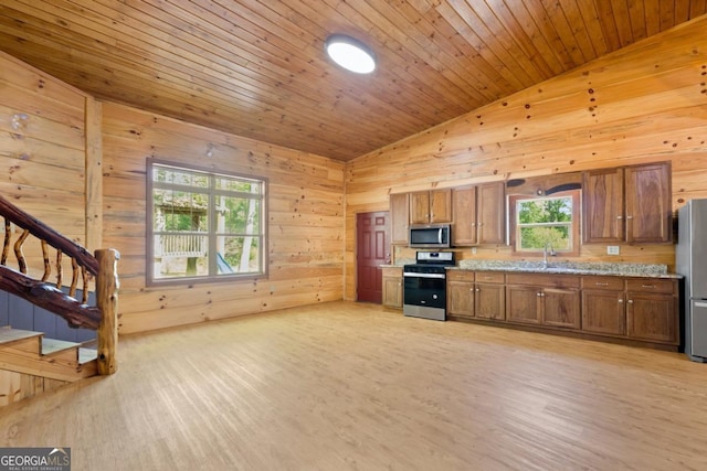 kitchen featuring sink, wood ceiling, light wood-type flooring, appliances with stainless steel finishes, and wooden walls