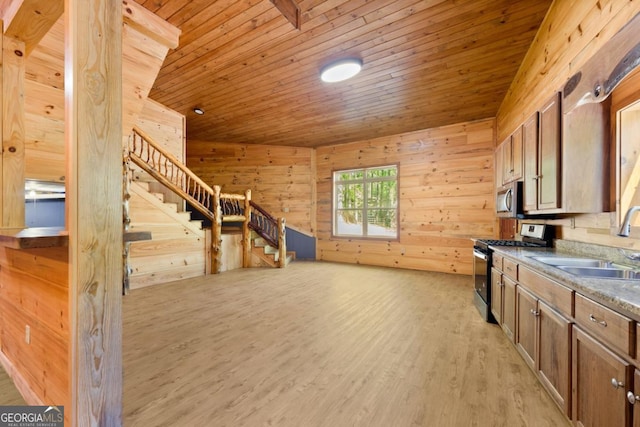 kitchen with sink, wooden ceiling, light wood-type flooring, appliances with stainless steel finishes, and wooden walls