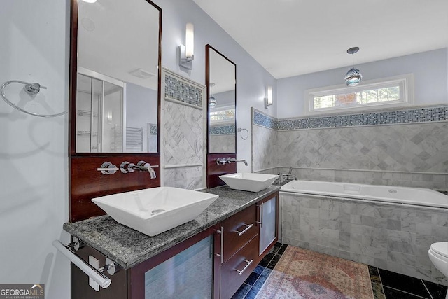 bathroom featuring tiled tub, vanity, tile patterned flooring, and toilet