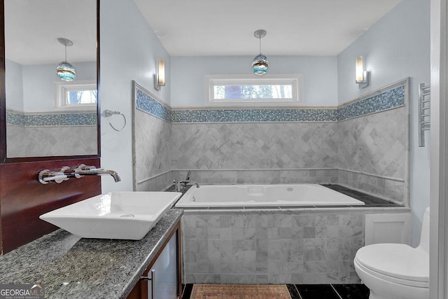 bathroom with vanity, a wealth of natural light, a relaxing tiled tub, and toilet