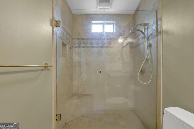 bathroom with a shower with shower door and toilet