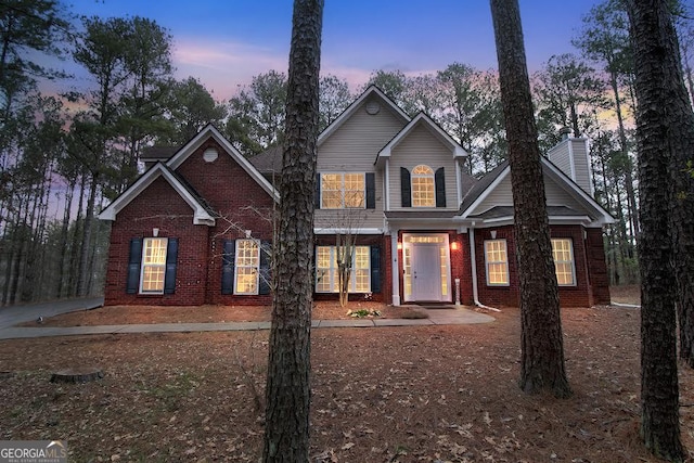 traditional-style house with a chimney and brick siding