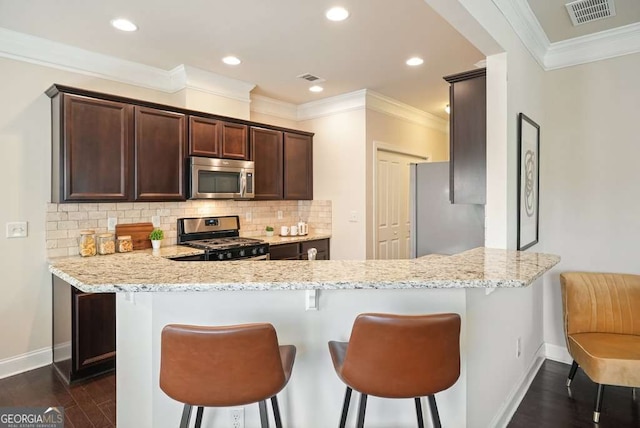 kitchen with light stone countertops, appliances with stainless steel finishes, and kitchen peninsula