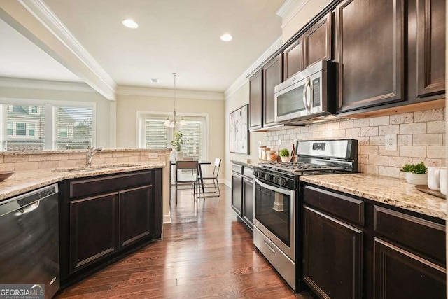 kitchen featuring sink, hanging light fixtures, ornamental molding, dark brown cabinetry, and stainless steel appliances