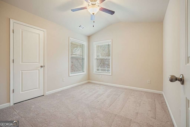 empty room featuring vaulted ceiling, light colored carpet, and ceiling fan