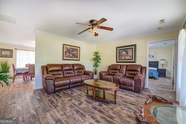 living room with visible vents, ornamental molding, and wood finished floors