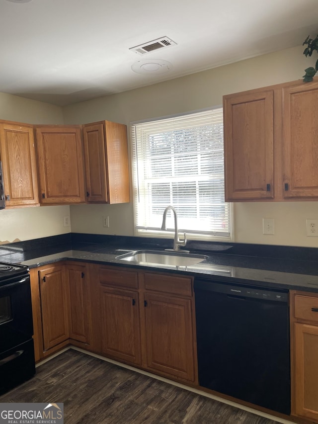 kitchen featuring dark countertops, a sink, brown cabinets, black appliances, and dark wood-style flooring