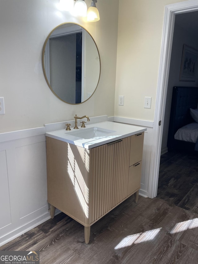 bathroom with vanity, wood finished floors, and wainscoting