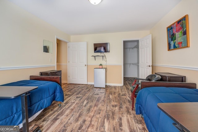 bedroom with a walk in closet, dark wood-type flooring, and a closet