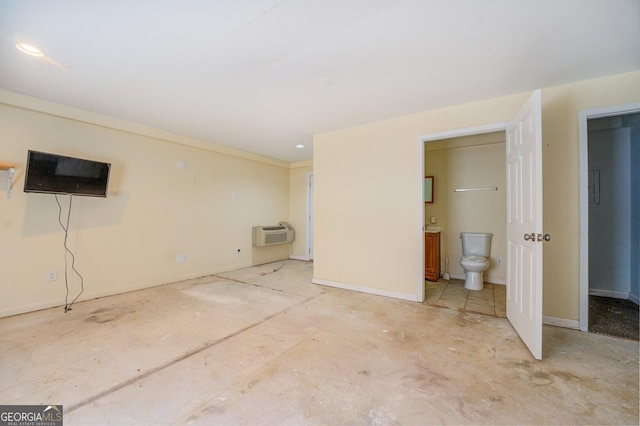 interior space featuring an AC wall unit, baseboards, and ensuite bathroom