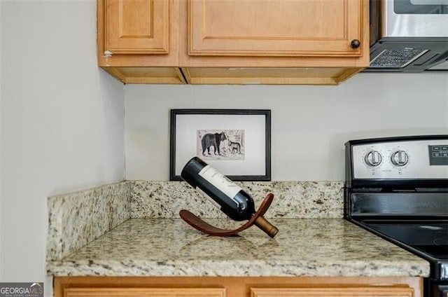 details featuring stainless steel range with electric stovetop, range hood, and light stone countertops