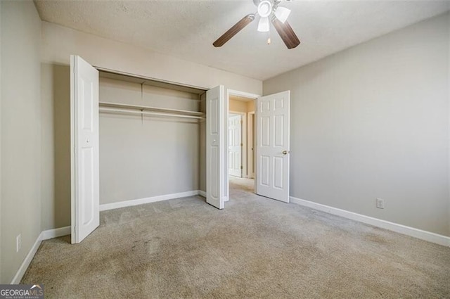 unfurnished bedroom featuring light carpet, a textured ceiling, a closet, and ceiling fan