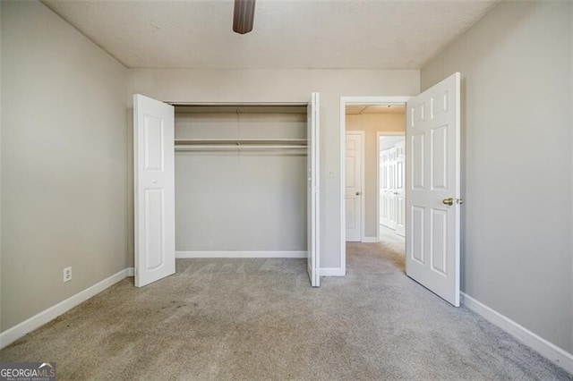 unfurnished bedroom with ceiling fan, light colored carpet, and a closet