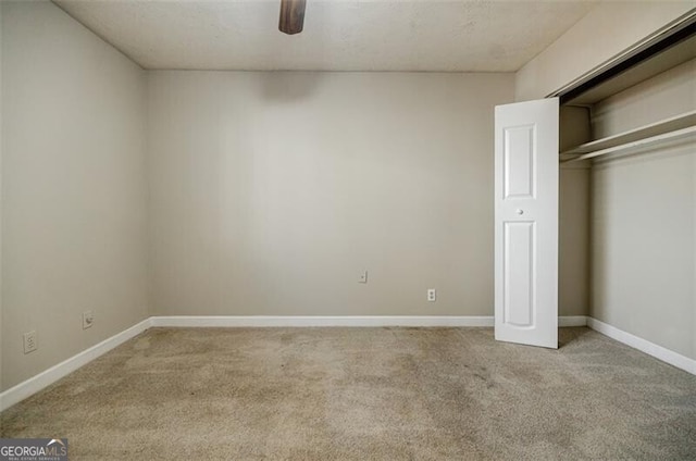 unfurnished bedroom featuring ceiling fan, a closet, and light carpet