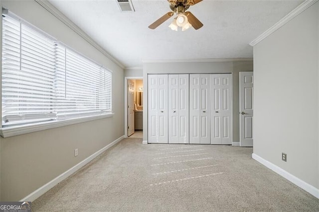 unfurnished bedroom with crown molding, a closet, ceiling fan, and light carpet