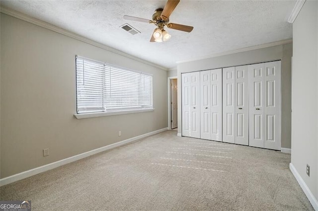 unfurnished bedroom with crown molding, light colored carpet, a textured ceiling, and a closet