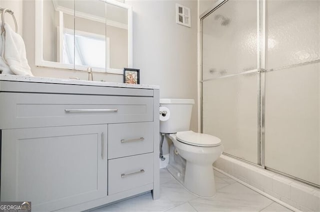 bathroom featuring vanity, toilet, and a shower with shower door