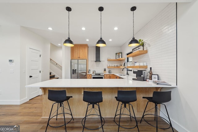 kitchen with sink, stainless steel appliances, a kitchen bar, kitchen peninsula, and light wood-type flooring