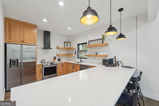 kitchen with wall chimney exhaust hood, sink, appliances with stainless steel finishes, kitchen peninsula, and pendant lighting