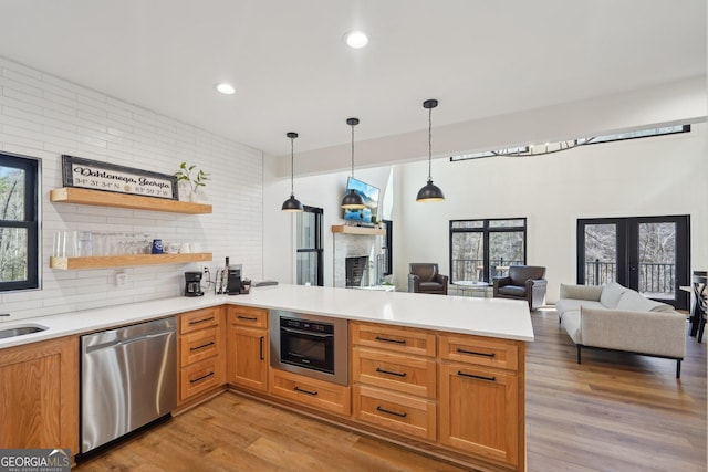 kitchen featuring light hardwood / wood-style flooring, stainless steel dishwasher, kitchen peninsula, pendant lighting, and wall oven