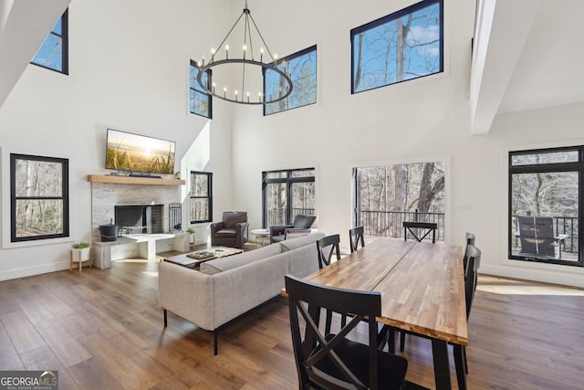 living room featuring a stone fireplace, hardwood / wood-style floors, and a chandelier