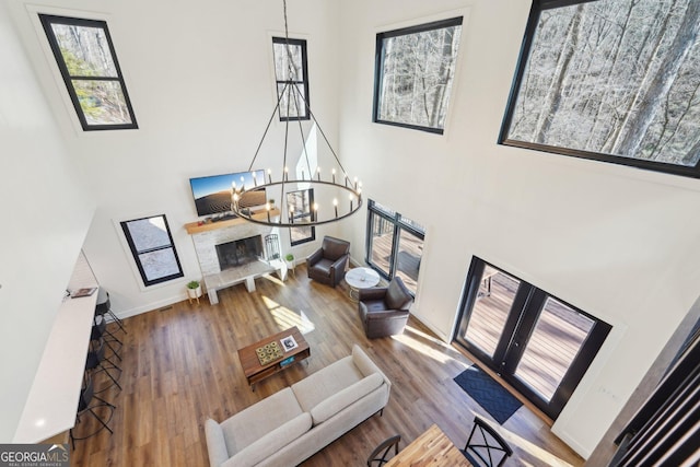 living room featuring a notable chandelier, a healthy amount of sunlight, hardwood / wood-style floors, and a high ceiling