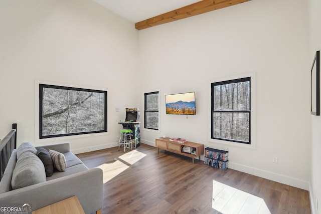 living room featuring a towering ceiling, dark hardwood / wood-style floors, and beamed ceiling