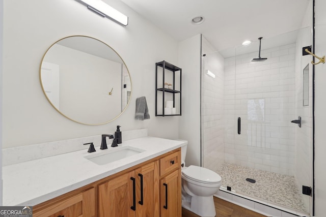 bathroom with vanity, a shower with shower door, and toilet