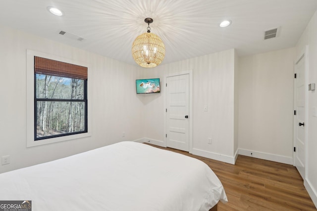 bedroom with hardwood / wood-style floors and a chandelier