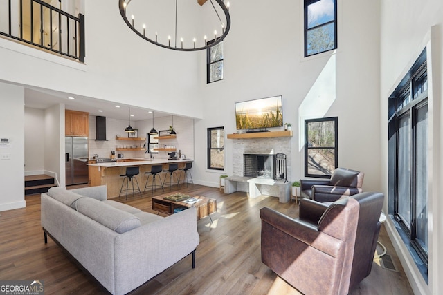 living room featuring an inviting chandelier, hardwood / wood-style floors, and a stone fireplace