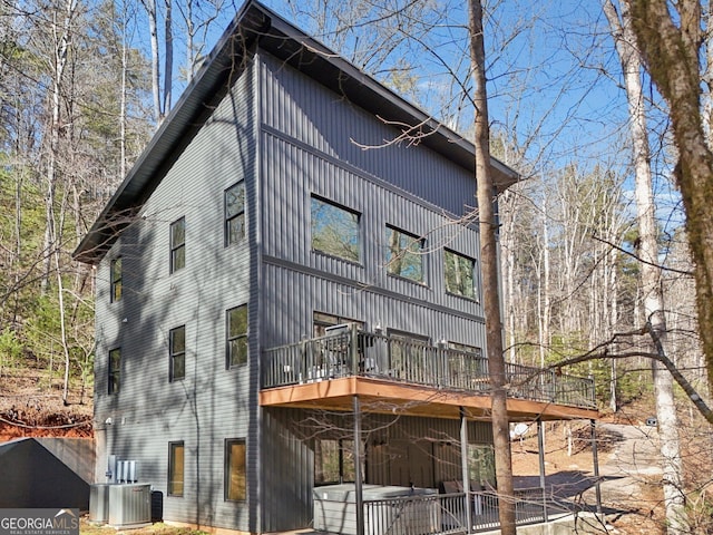 rear view of property featuring a wooden deck and cooling unit