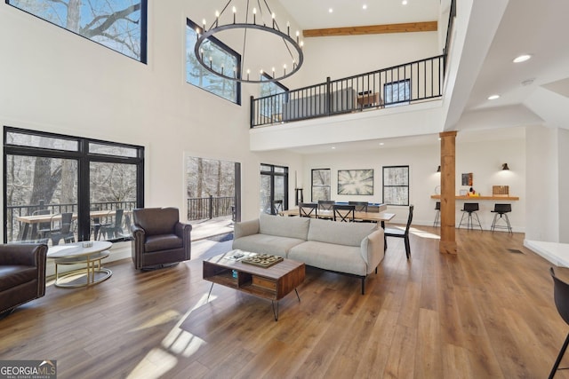 living room featuring an inviting chandelier, hardwood / wood-style floors, and decorative columns