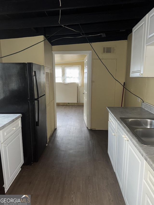 kitchen with white cabinetry, black fridge, sink, and dark hardwood / wood-style flooring