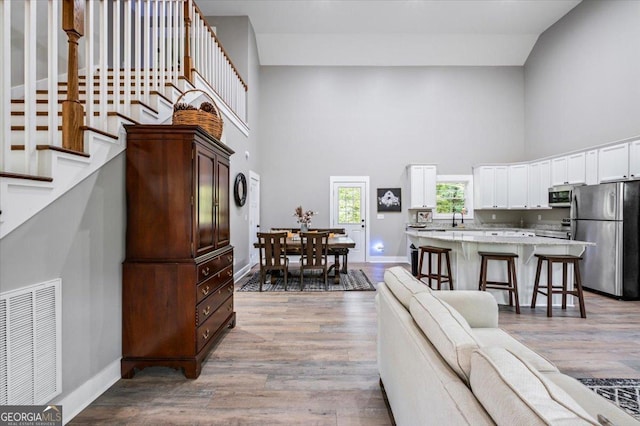 living room with a high ceiling, sink, and light wood-type flooring