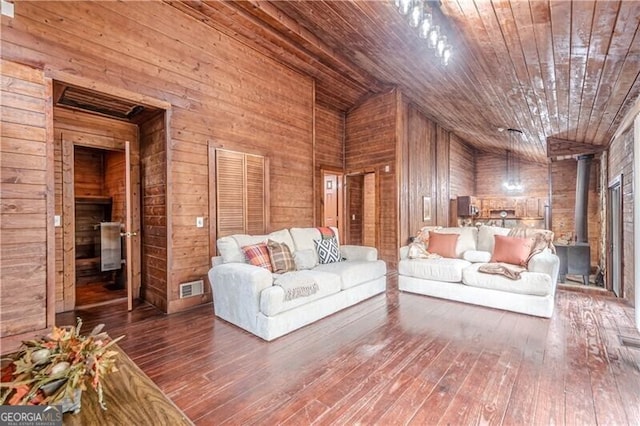 unfurnished living room with hardwood / wood-style flooring, a wood stove, wood ceiling, and wood walls