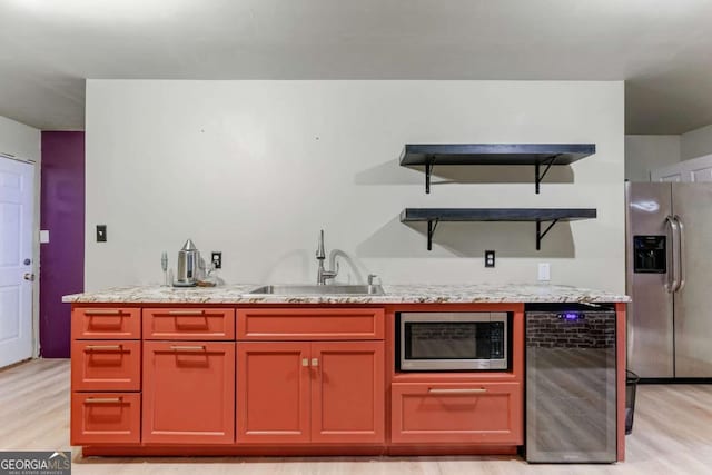 kitchen featuring beverage cooler, stainless steel appliances, a sink, light stone countertops, and open shelves